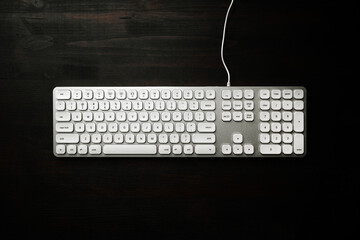 Top view of white computer keyboard on black office desk