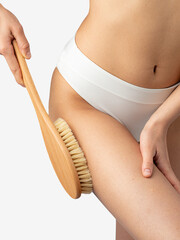 Woman rubbing her thigh with a dry massage brush