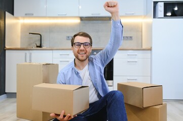 Young caucasian man at a new home with cardboard boxes