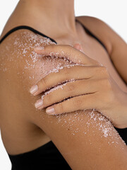 Woman applying scrub cosmetics on her skin on her shoulder