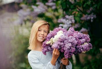 Fototapeta premium beautiful young girl with a bouquet of lilacs, a girl in lilacs, lilacs in spring. Young beautiful brunette girl posing with a bouquet of lilac