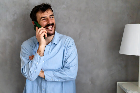 Happy caucasian man laughing during smartphone conversation.