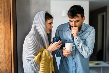 Sick man and woman wrapped in blankets suffering from cold or flu