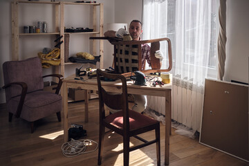 Man working in a small home workshop for furniture repairing and restoration.