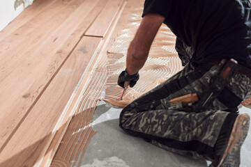 Professional handyman installing laminate flooring in a new apartment.