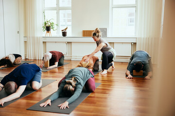 Yoga teacher helping a student do the child's pose