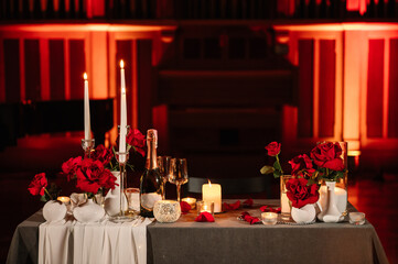 Location for surprise proposal at night. Luxury romantic date. Decoration, flower petals, burning candles. Table setting in restaurant for the event. Candlelight for couple on Valentine's day.