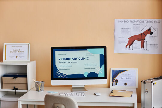 Computer on desk near certificates and dog diagram in veterinary clinic