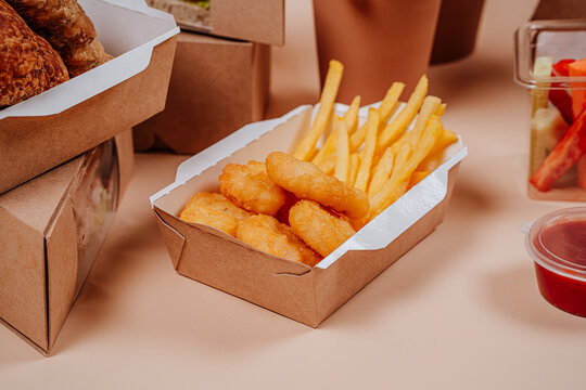 French fries and chicken nuggets in container against beige background