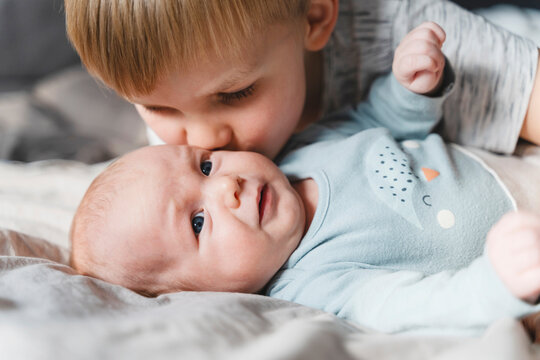 Brother kissing baby brother on cheek at home