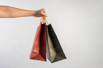 Red and green paper shopping bag in hand on white background.