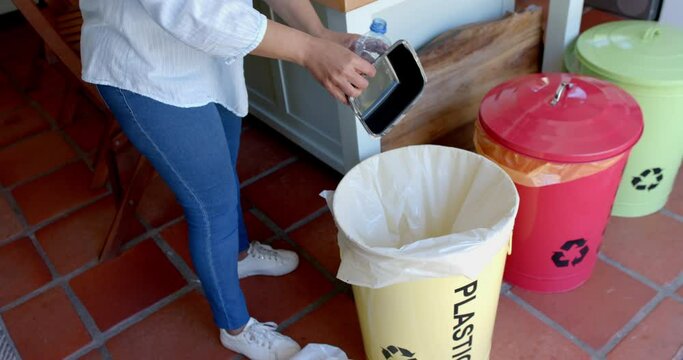Senior biracial woman segregating waste at home, slow motion