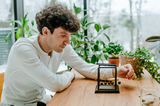 Businessman playing with newton's cradle at desk in office