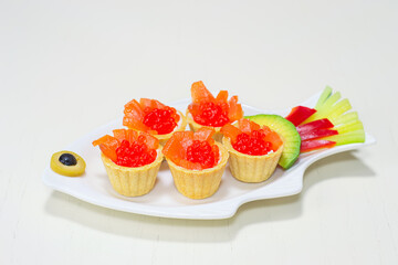 Red caviar and pieces of salmon, in tartlets on a white plate. Selective focus