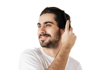 Young attractive brunette man with beard brushing his long and curly hair against white studio...