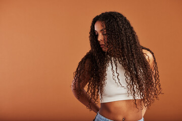Young black woman looking sideways against an orange background
