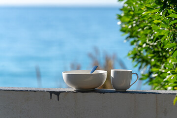 Frühstück Schüssel und Tasse beim Camping auf einer Mauer beim Meer