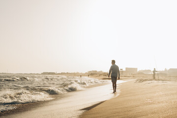 Photo of a man in sunglasses walking along the Black Sea shore. The stormy sea sparkling with...