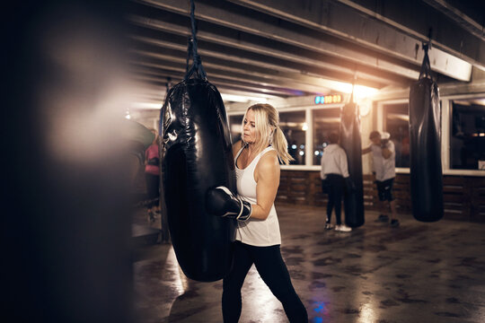 Mature woman doing a punching bag workout in a boxing gym