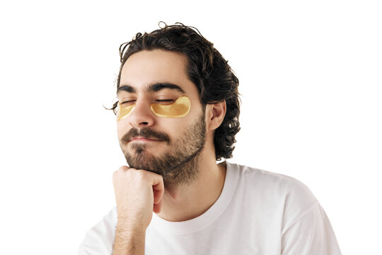 Close up portrait of young attractive man closed eyes with hydrogel patches under eyes against swelling and bruising against white studio background. Concept of facial care routine, cosmetic product.
