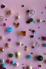 Various colorful beads on bright pink background. Top view.