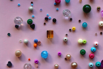 Various colorful beads on bright pink background. Top view.