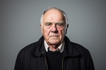 Portrait of an elderly man in a black hoodie on a gray background