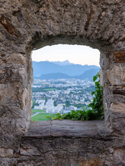 Steinfenster mit Blick auf Alpenstadt im Tal
