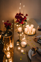 Romantic dinner setup at night. Wine glasses, flowers. Table setting for couple, Valentine's Day evening, burning candles for surprise marriage proposal. Candle light date in restaurant. Top view