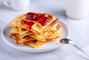 Belgian waffles with strawberry jam on a white background