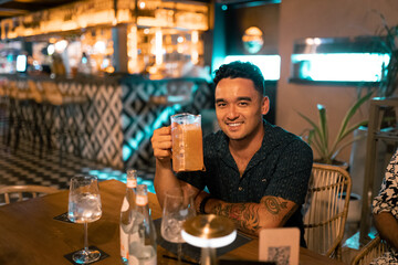 Young Hawaiian Man Smiling with Beer Jar in Bar Setting