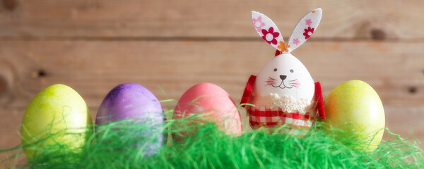 Row of colorful Easter eggs and bunny rabbit decoration on wooden banner background