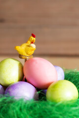 Row of colorful Easter eggs and yellow chicken decoration on wooden background, copy space