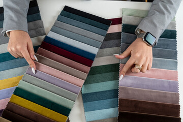 Fototapeta na wymiar female hand show fabric catalog for choose bright rich color for new sofa