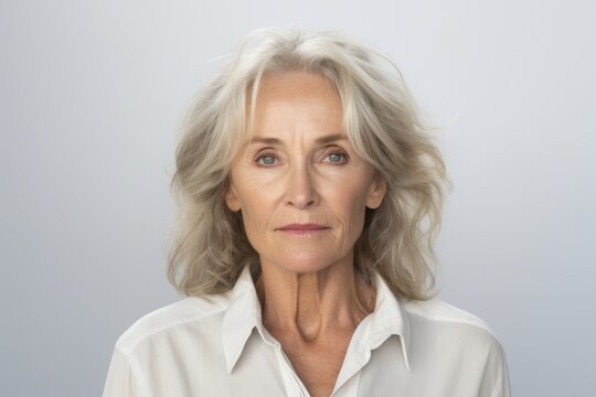 Portrait of senior woman looking at camera with serious expression against grey background