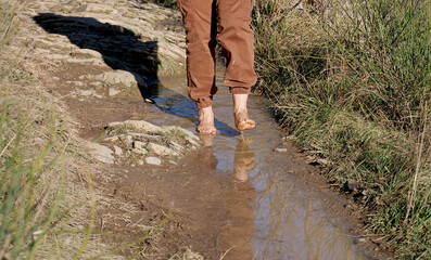 Walking barefoot in a natural sensory tactile trail with stone, puddles and mud