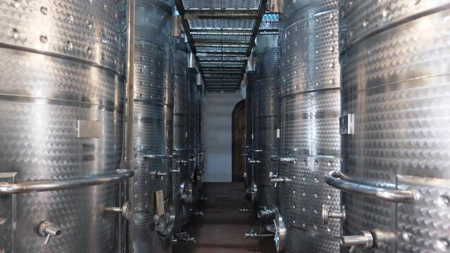 Rows of large stainless steel wine distillation tanks. Steel barrels for fermentation and wine production at the winery.