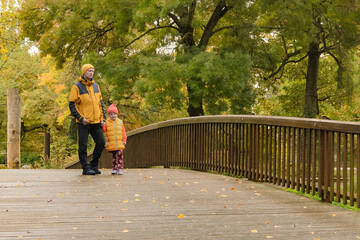 father and five-year-old daughter in fall park on bridge
