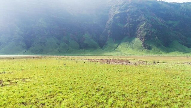 Bromo Mountain's savanna unfolds in cinematic splendor through captivating drone dolly shots, revealing the stunning expanse and natural beauty.