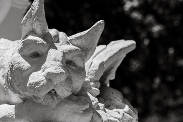 Closeup of a stone gargoyle sculpture on a wall in grayscale