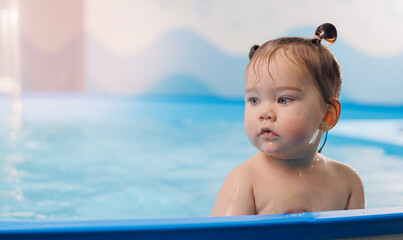 Fototapeta na wymiar Little baby swimmer. Cute happy kid girl floating in swimming pool. Sport activity for health concept