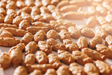 Closeup peanut shape biscuit production on conveyor belt, Food industry factory. Modern line for bakery cookies, sunlight