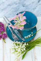Spring Table Setting with Blue Cutlery and Lilac Flowers on a Wooden Background.Floral Table Decor