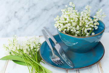 Spring Table Setting with Blue Cutlery and Lily of the Valley  Flowers on a Wooden Background....