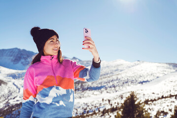 Beautiful  Woman using mobile phone in the Winter Snowy Mountain .Woman making selfie 