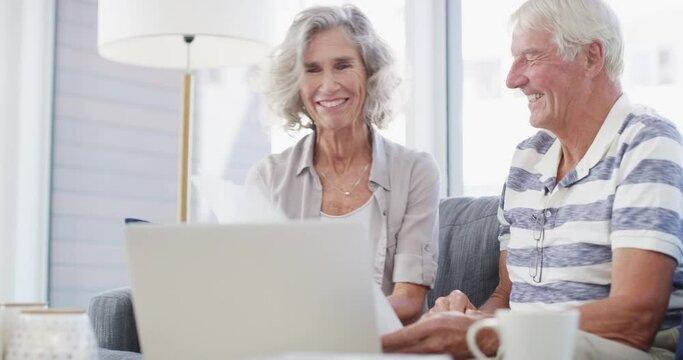Senior couple, laptop and documents for financial assets, investment portfolio and budget for mortgage at home. Happy man, woman and bills for online banking, retirement savings and insurance policy