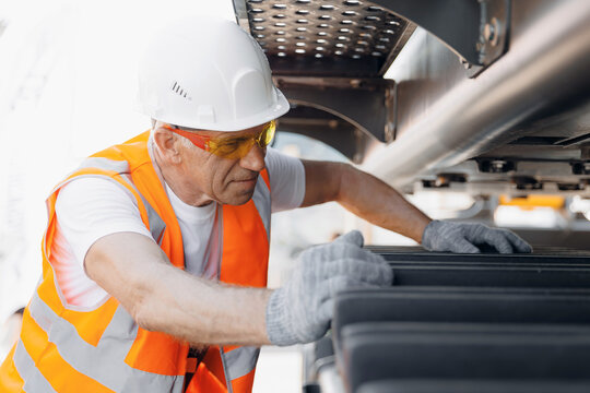 Repair of Industrial truck. Industry driver in hard hat checks breakdowns of excavator, bulldozer of mining