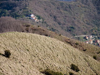 Green hills of the Ligurian hinterland in Italy with tourists walking in the distance