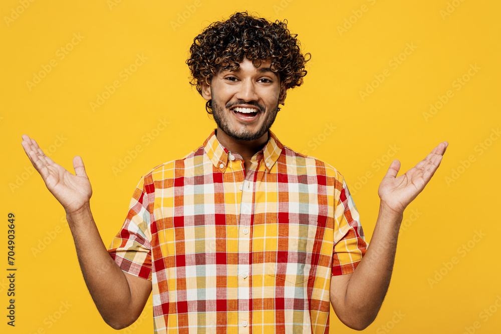 Wall mural Young excited overjoyed surprised cool fun shocked Indian man he wearing shirt casual clothes looking camera spread hands isolated on plain yellow color background studio portrait. Lifestyle concept.