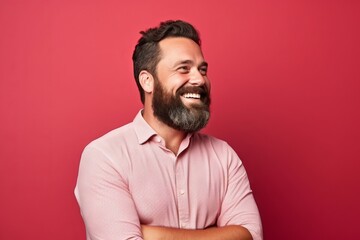 Portrait of a happy bearded man with crossed arms against red background